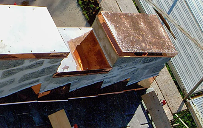 Custom copper chimney cap and flashing above a fresh shingle roof