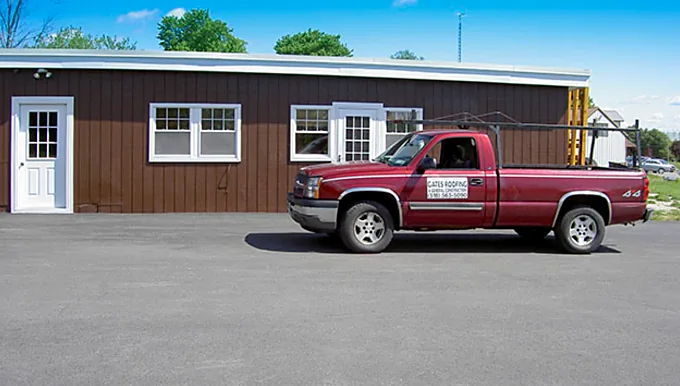Gates Roofing's brown board-and-batten office on Route 9 with a company pickup out front