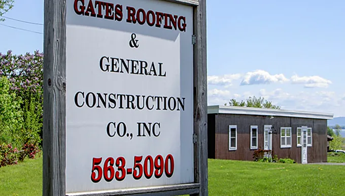 The Gates Roofing & General Construction Co., Inc. roadside sign on Route 9, with the office and Lake Champlain behind it