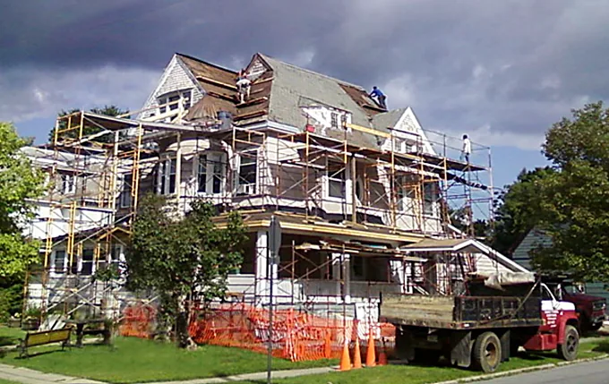 Victorian re-roof in progress with safety fencing and a Gates dump truck at the curb