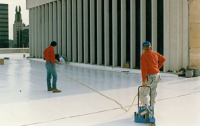 Crew installing a white single-ply membrane roof on a downtown federal building